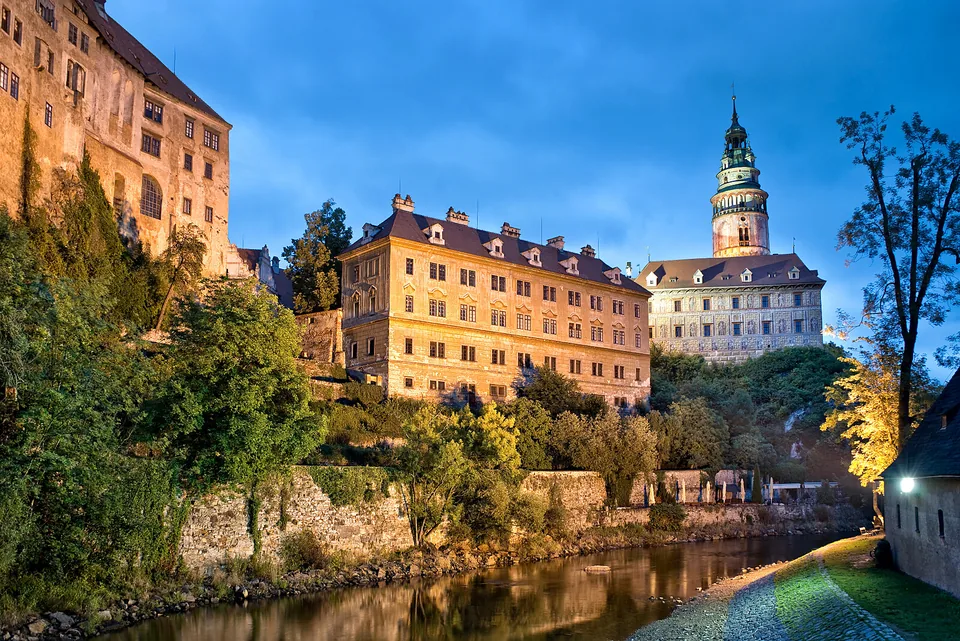 Krumlovský zámek s malovanou věží nad řekou Vltavou za modré hodiny